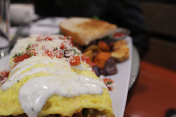 Wakey Wakey Eggs and Bakey omelette with toppings on a plate, served with toast and side vegetables.